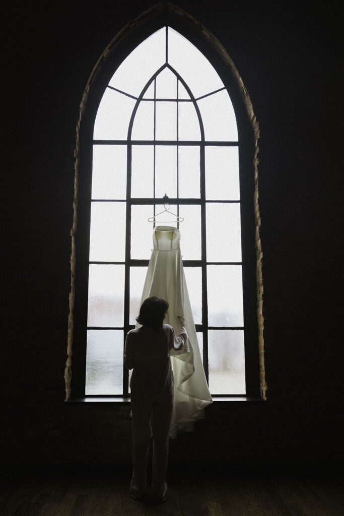 Bride with her dress at Clementine Hall wedding venue with arched stained glass windows in Nashville